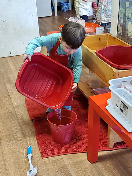 child using plastic bin to wash dishes