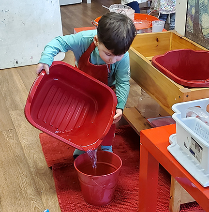 child using plastic bin to wash dishes