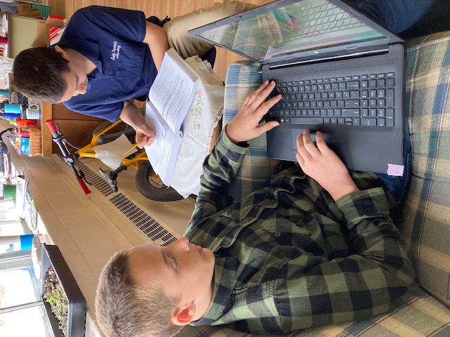 children writing stories with laptops and paper