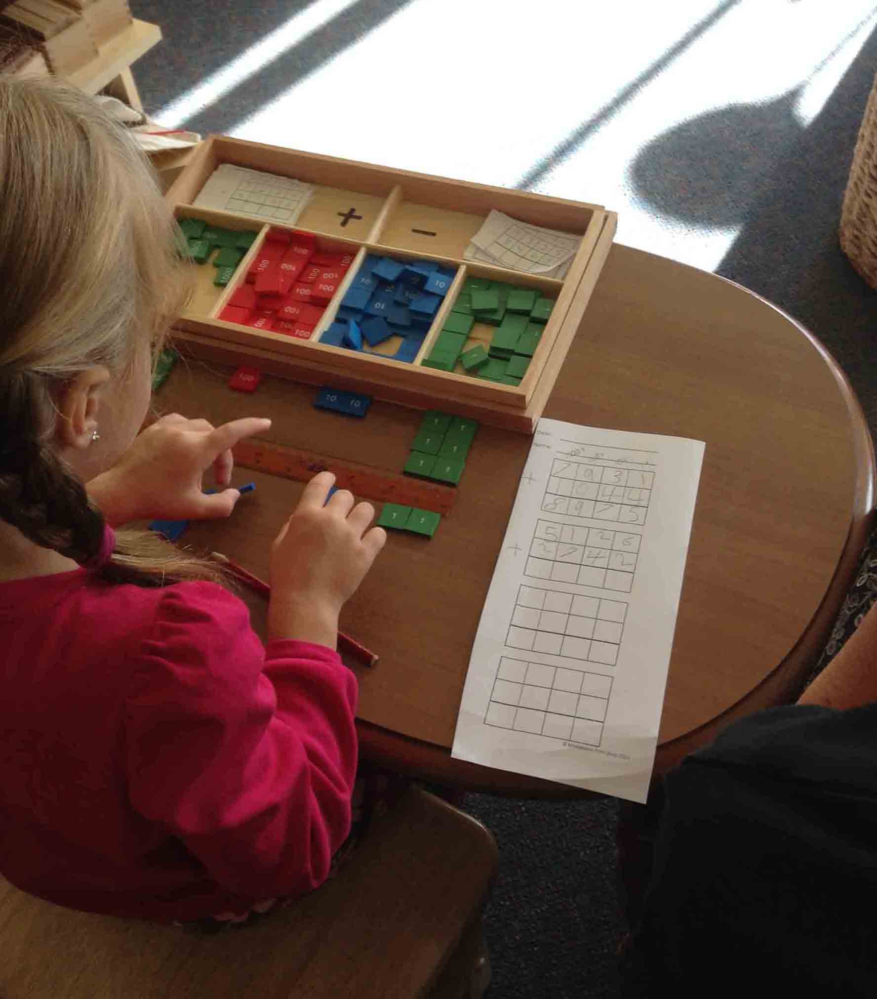 child counting small tiles with numbers on them