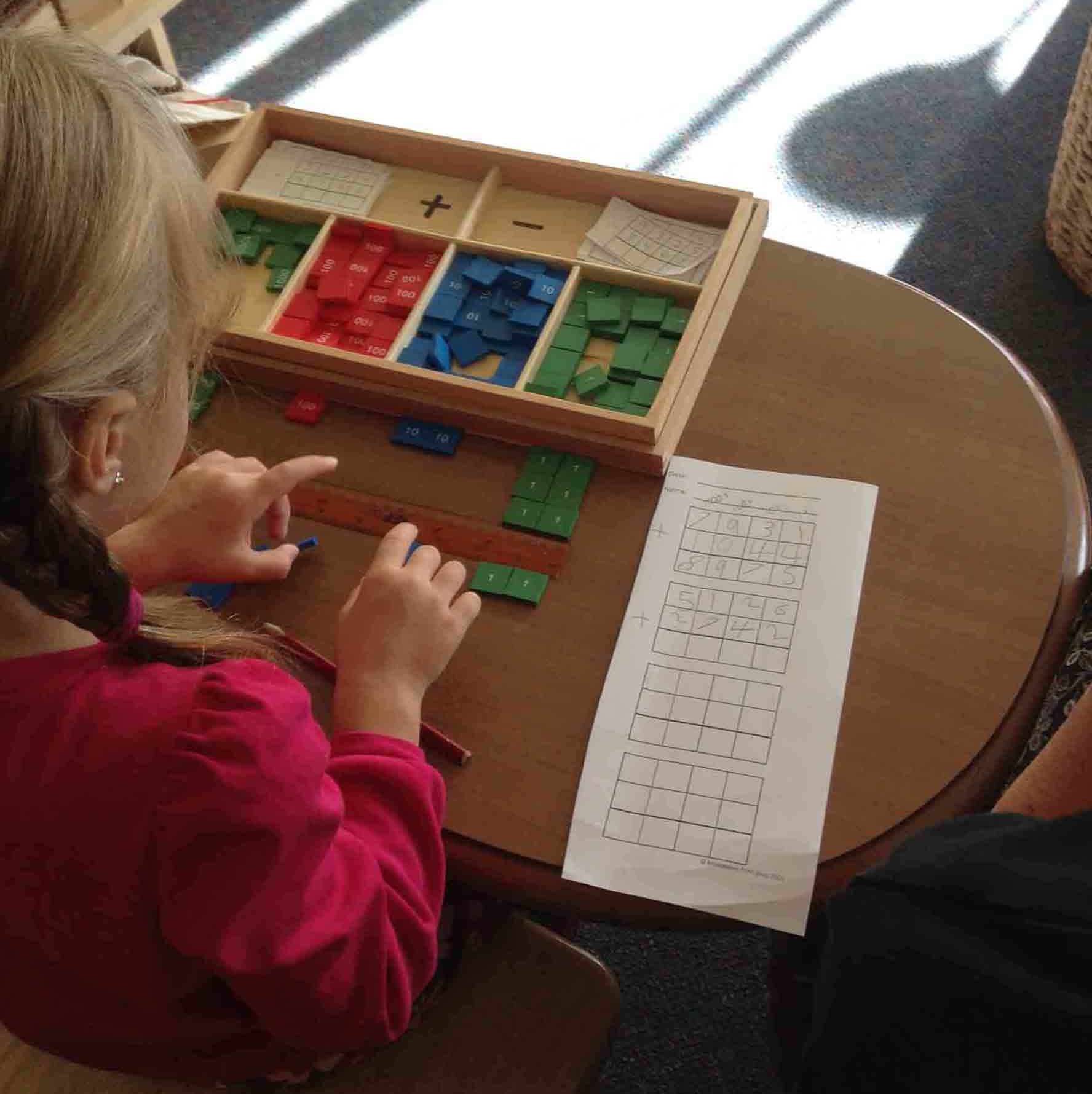 child playing with small tiles with numbers on them