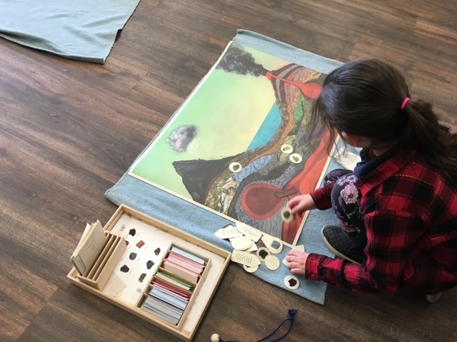 child sitting on floor with diagram of a volcano